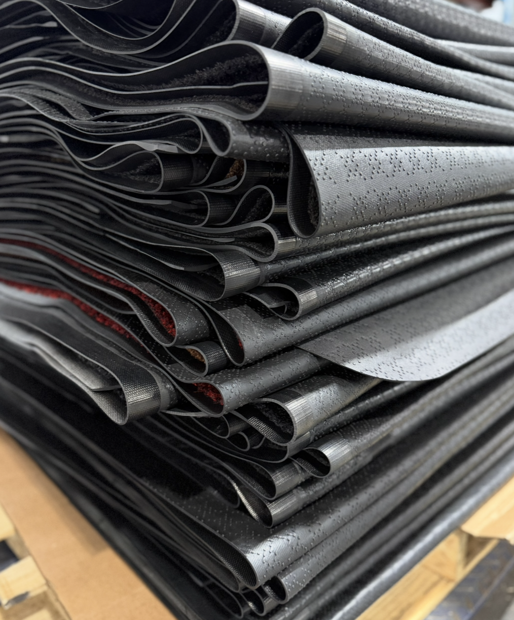 Stack of damaged walk-off mats ready for repair evaluation